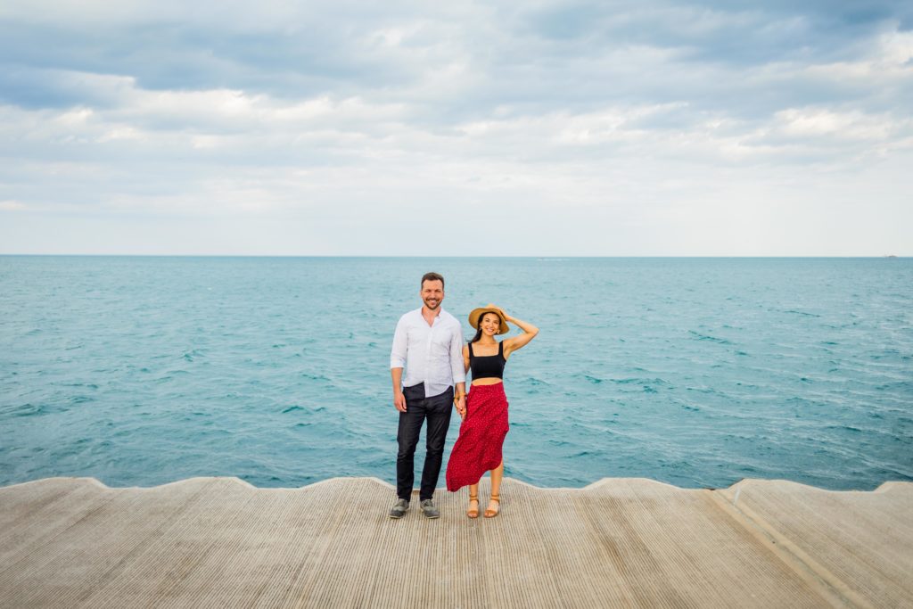 Couple smile while holding hands in front of Lake Michigan