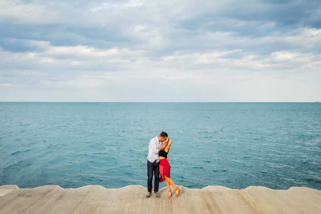 Couple kiss while holding hands in front of Lake Michigan