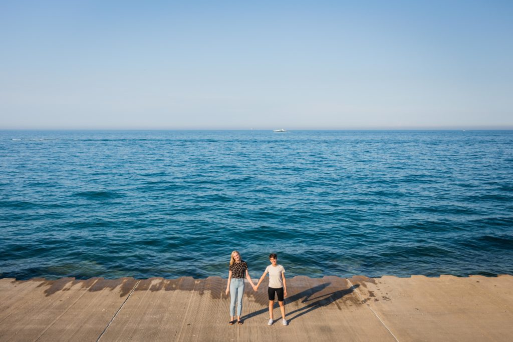 Queer women holding hands during their engagement session at belmont harbor