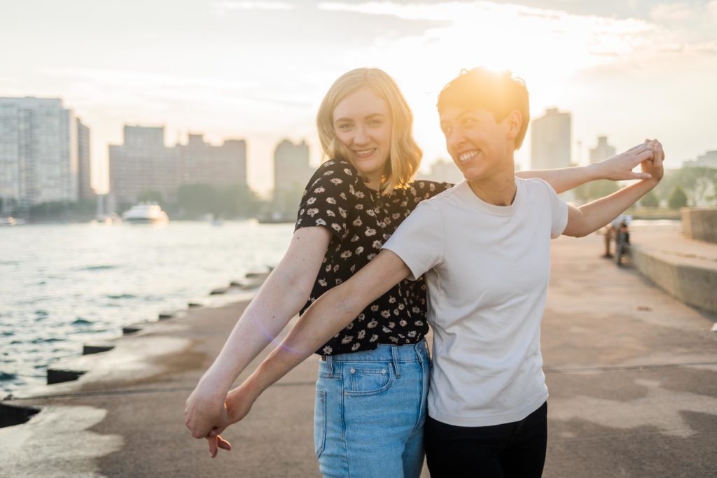 Couple holding outstretched arms with the sun shining behind them