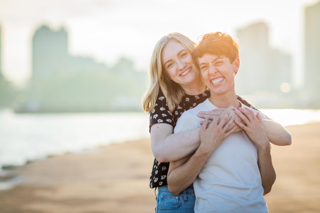 Woman holding her fiancé's chest from behind while smiling