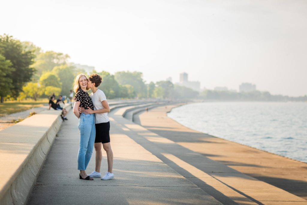 Women kissing and laughing while holding each other by Lake Michigan
