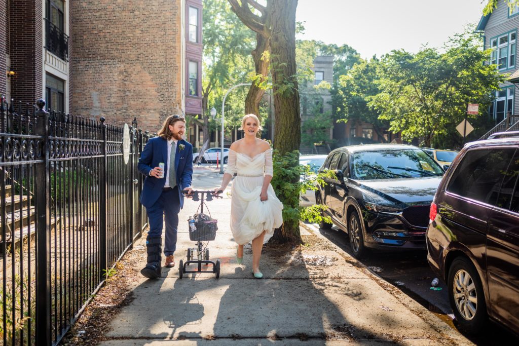 Bride and groom hold scooter while walking to their Big Star reception