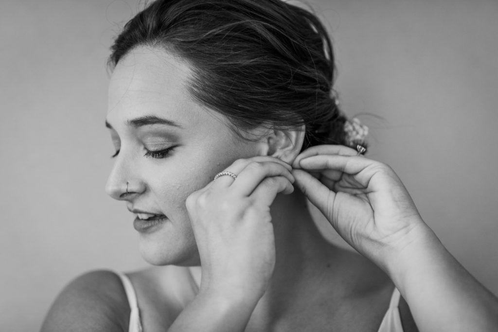 Bride putting on her earrings before her Big Delicious Planet Wedding