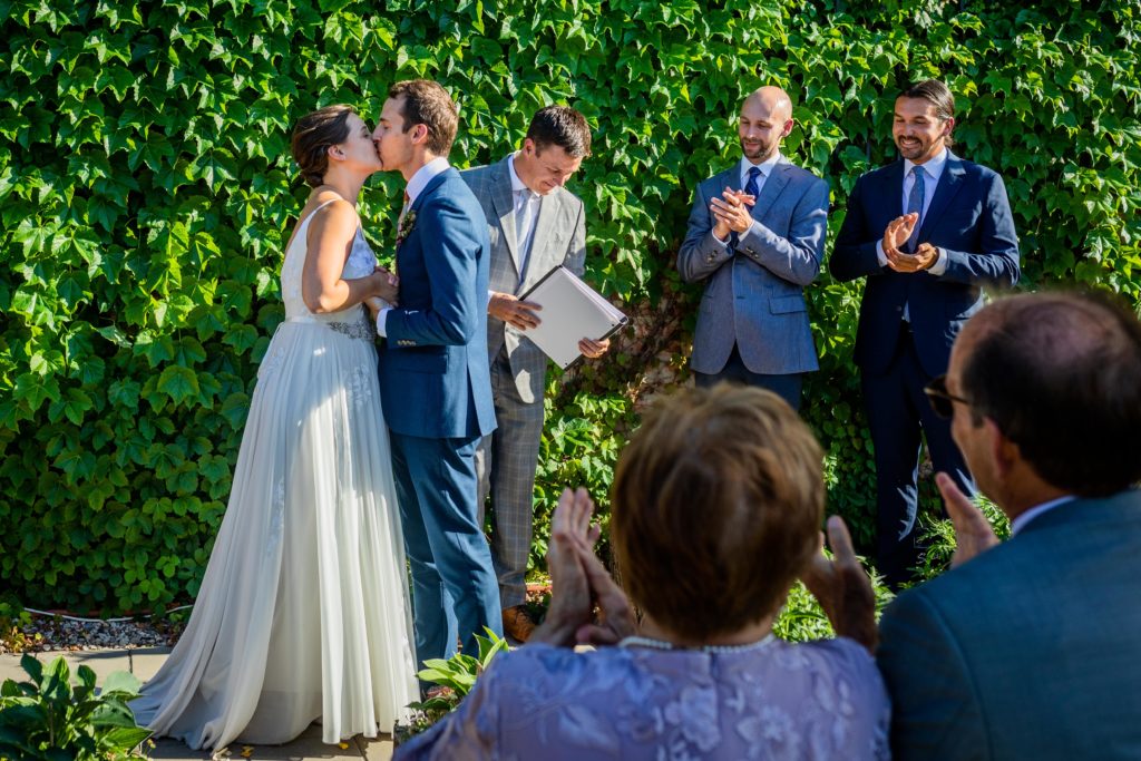 Bride and groom kissing while their family claps at Big Delicious Planet