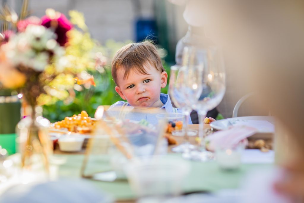 Small child with food on his face sitting at the dinner table