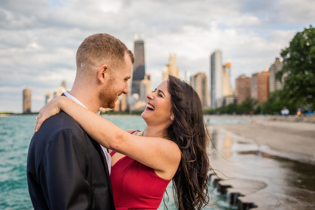 Couple laughing together next to the Chicago lakefront during their North Ave Beach Engagement Session