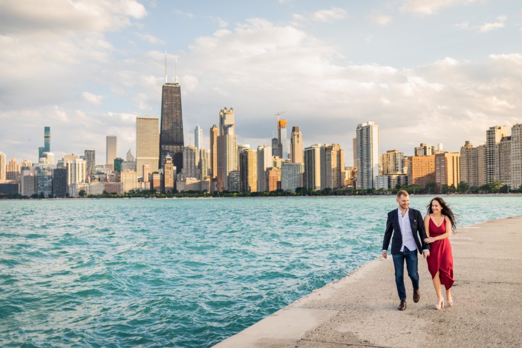 Man and woman walking together next to the Chicago Lakefront during their North Ave Beach Engagement Session