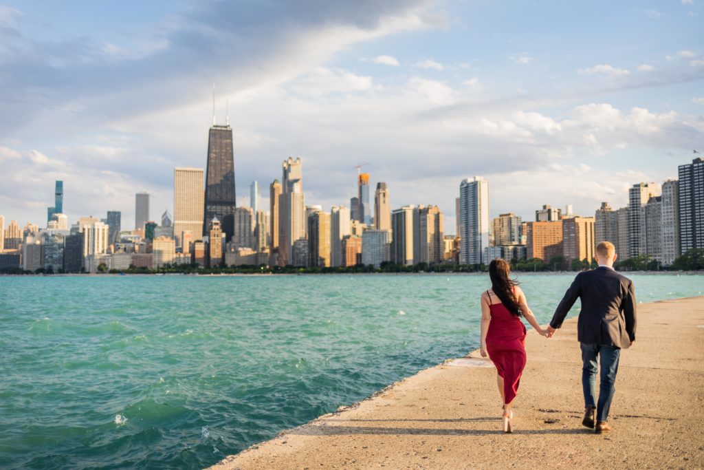 Man and woman walking together next to the water in Chicago during their North Ave Beach Engagement Session