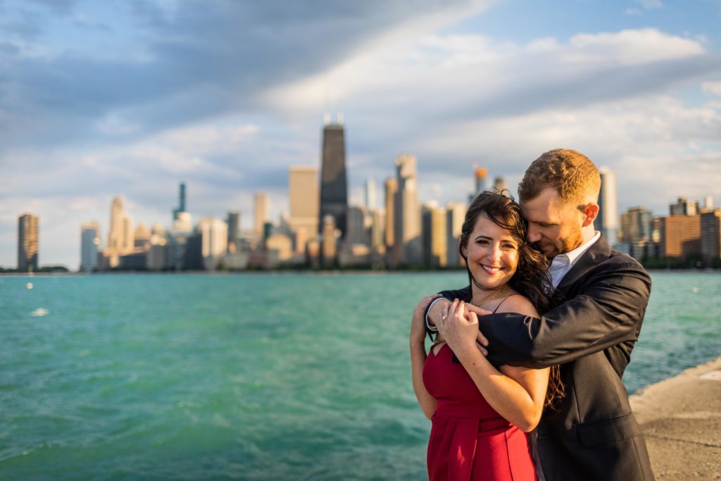 Man snuggles woman from behind as she smiles next to the Chicago Lakefront