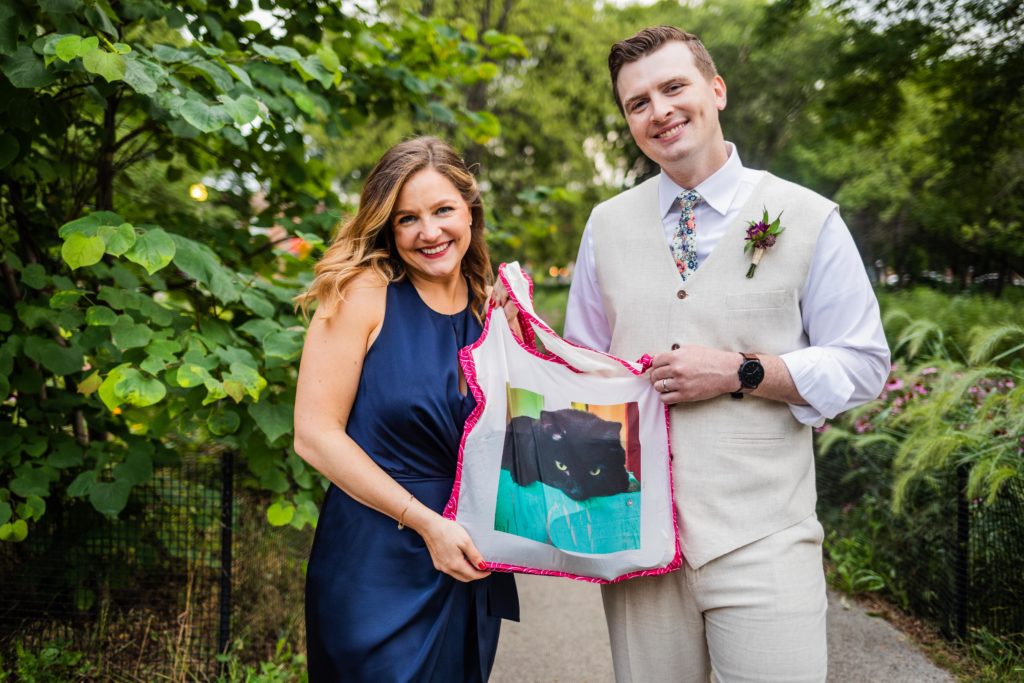 Bride and groom holding up a tote bag with a picture of their cat