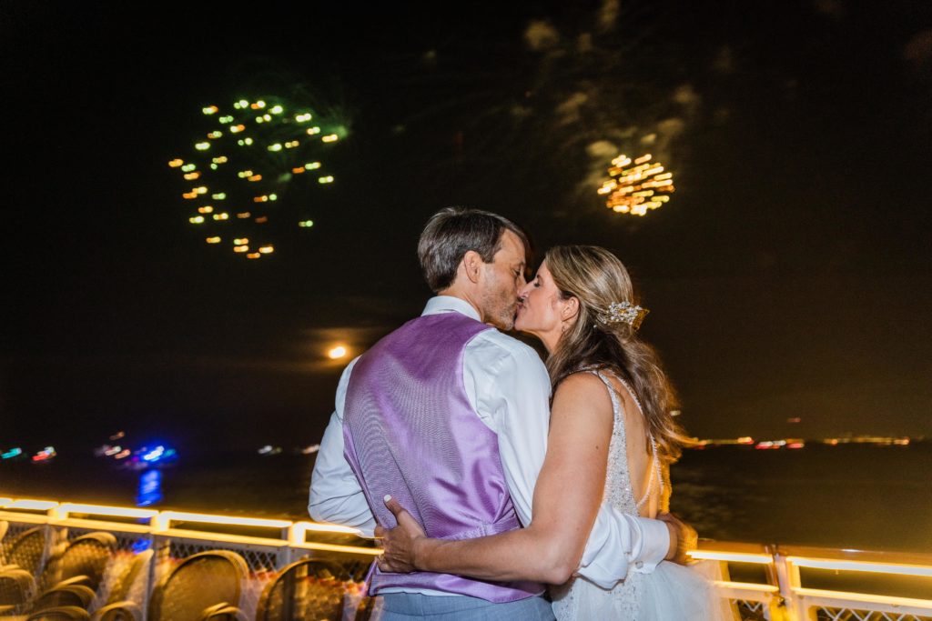 Bride and groom kissing with fireworks behind them on Chicago's First Lady Cruise
