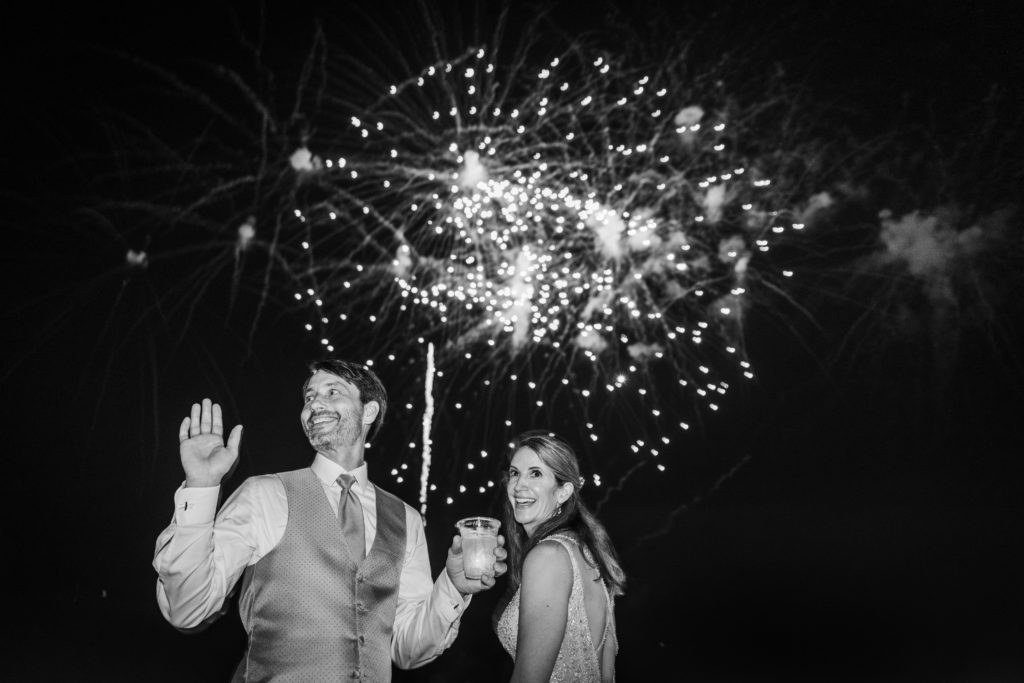 Bride and groom and laughing and smiling with fireworks behind them on Chicago's First Lady Cruise