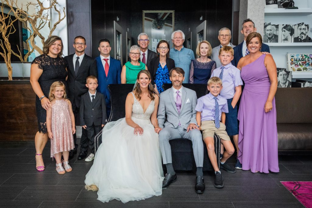 Bride and groom smiling for a family photo with extended family