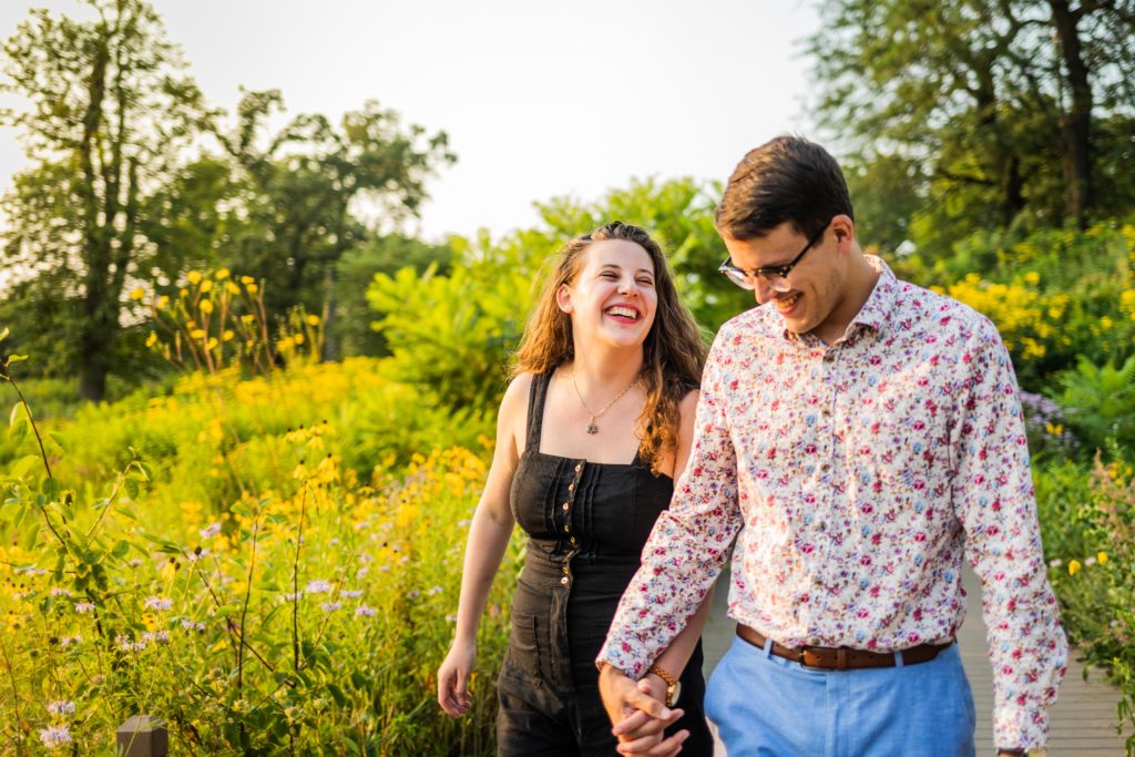 Couple walking and laughing together in the sunshine while holding hands