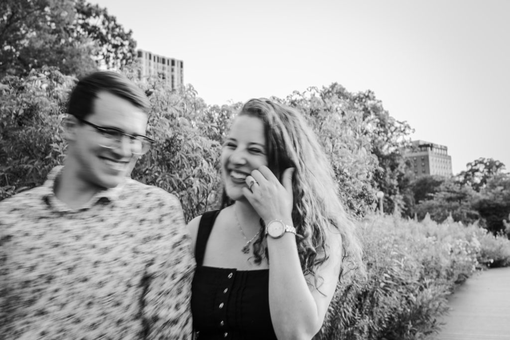 Man and woman laughing while walking as the woman pulls hair out of her face
