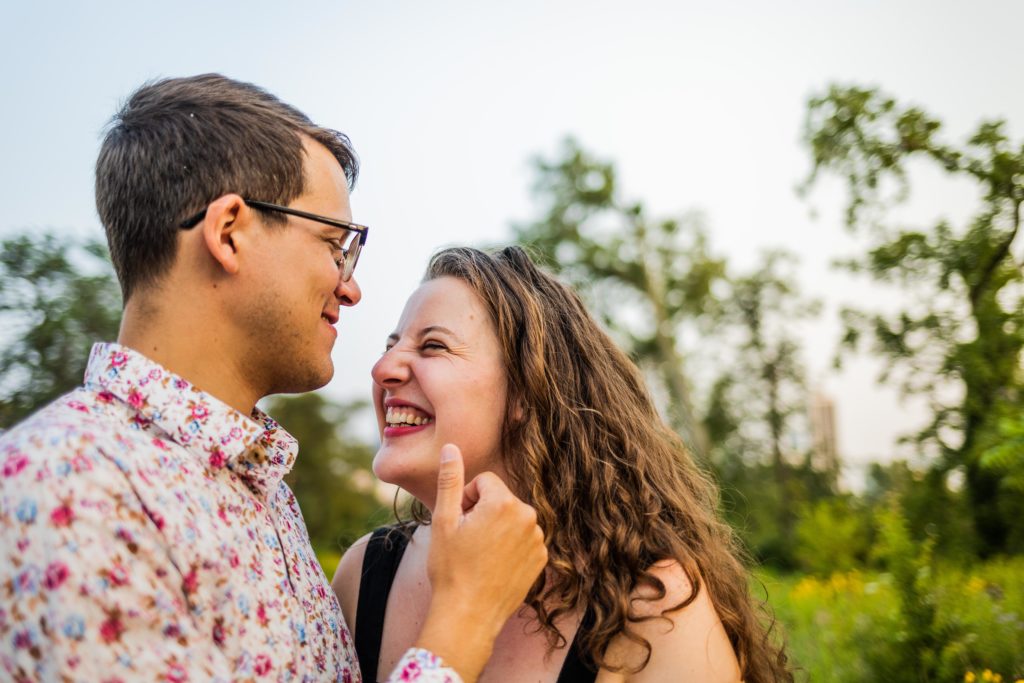 Man and women giggle in each other's faces during their south pond engagement session