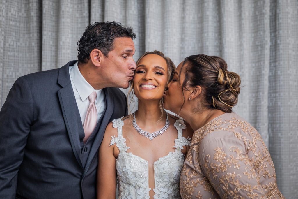 Parents of the bride kissing their daughter
