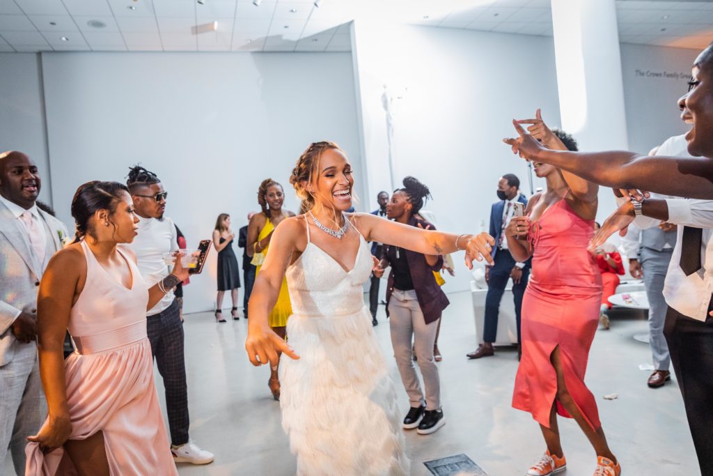 Bride laughing and smiling while on the dance floor with her friends