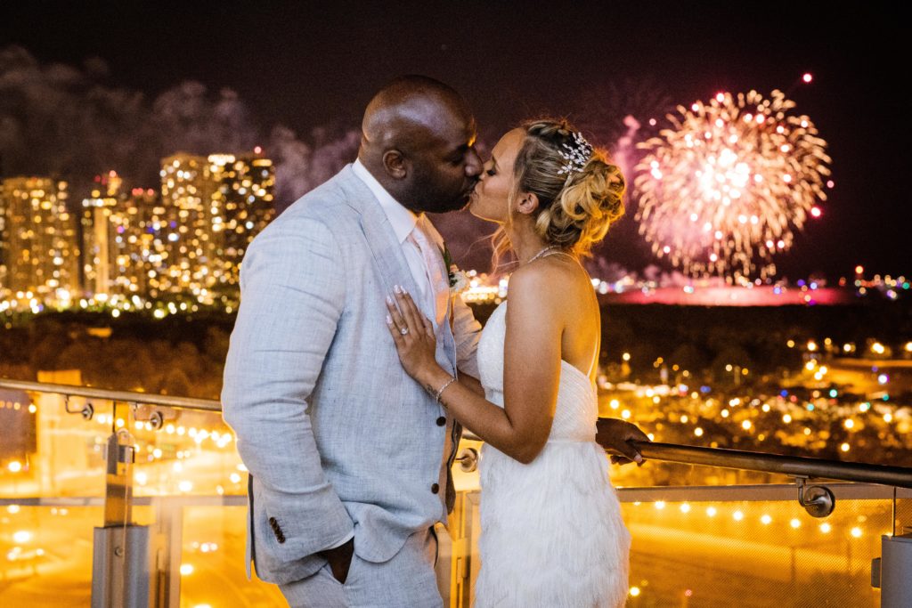 Bride and groom kissing during their wedding at Venue SIX10 while fireworks go off in the background