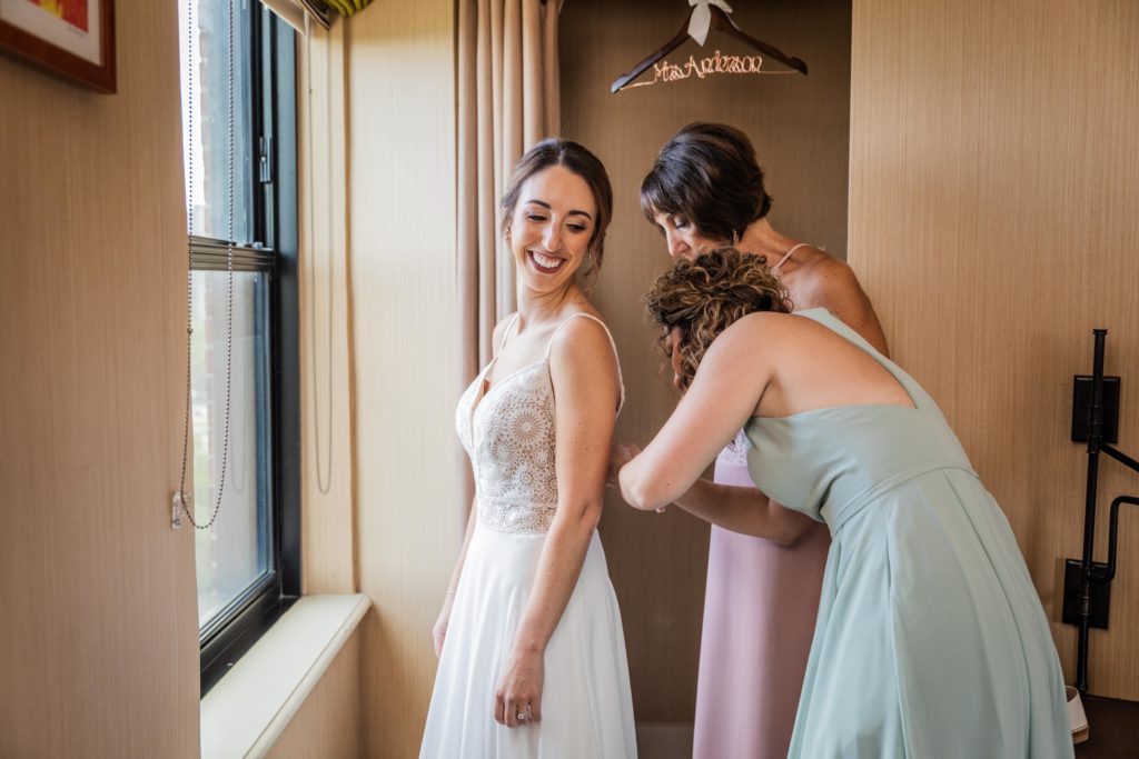 Bride's mom and sister helping her put on her wedding dress