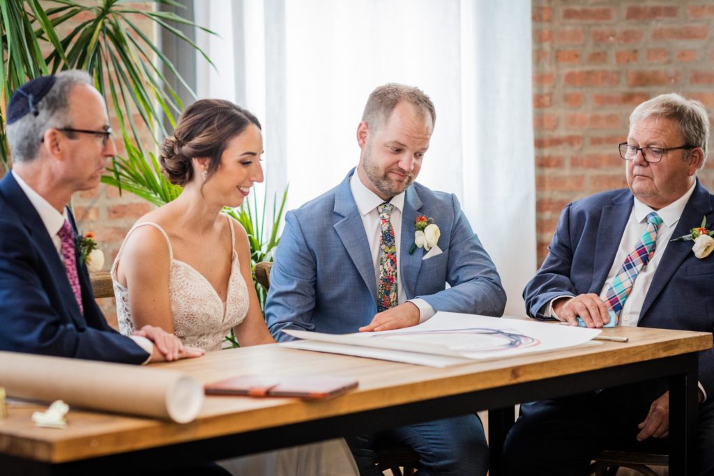Bride and groom reading the Ketubah with their fathers
