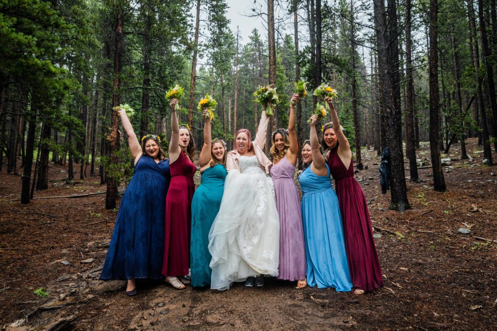 Bridesmaids throwing their bouquets up and making silly faces at the Dao House in Estes Park