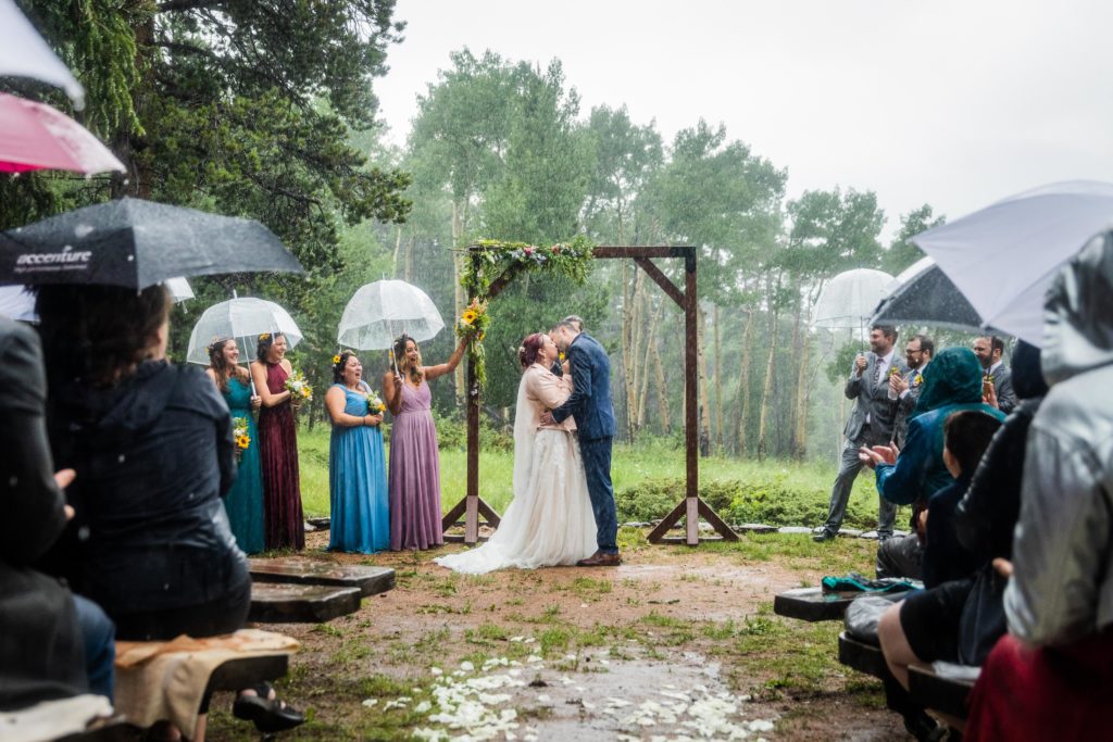 Bride and groom kiss in the rain at the altar at their Dao House Wedding in Estes Park
