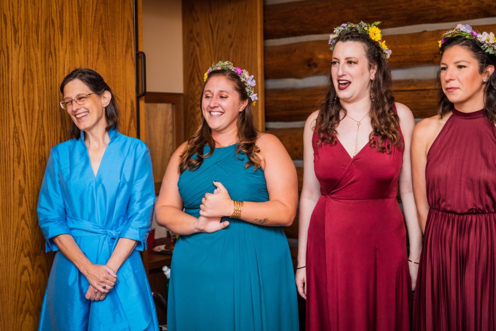 Bridesmaids smiling as they see the bride for the first time