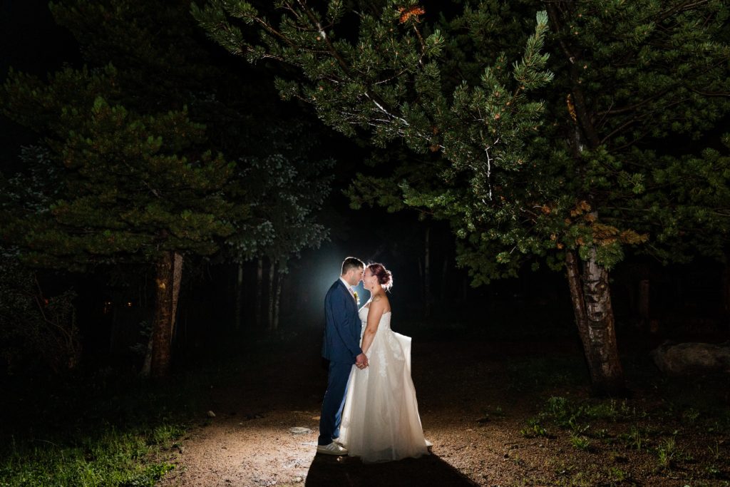 Couple touch foreheads while posing for a night portrait in the woods