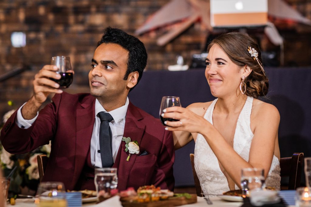Bride and groom holding up glasses at the dinner table