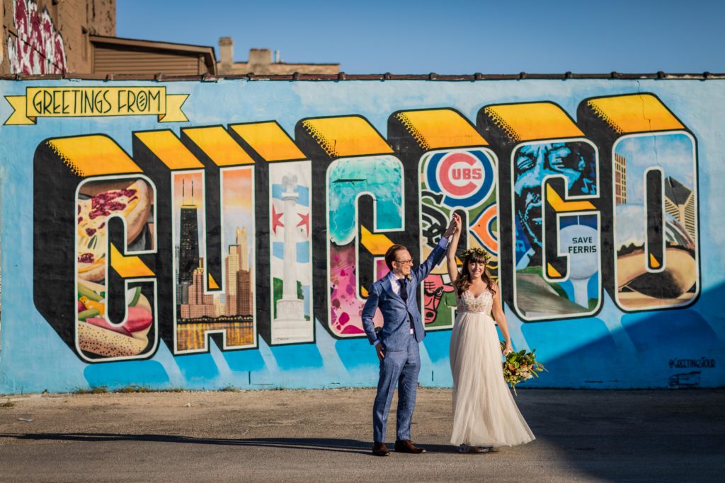 Bride and groom dancing in front of a mural in Chicago