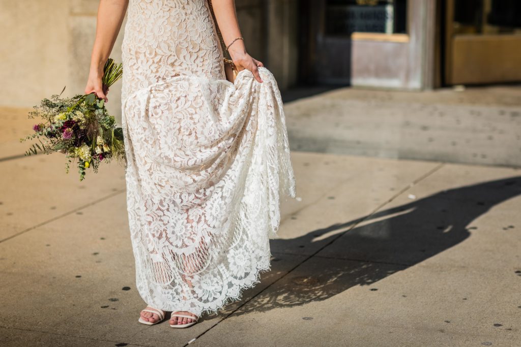 Bride holding her dress up in the sunlight in downtown Chicago