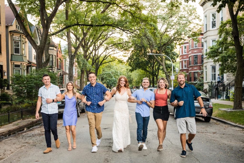Bride walking arm-in-arm with her friends down a street in Chicago