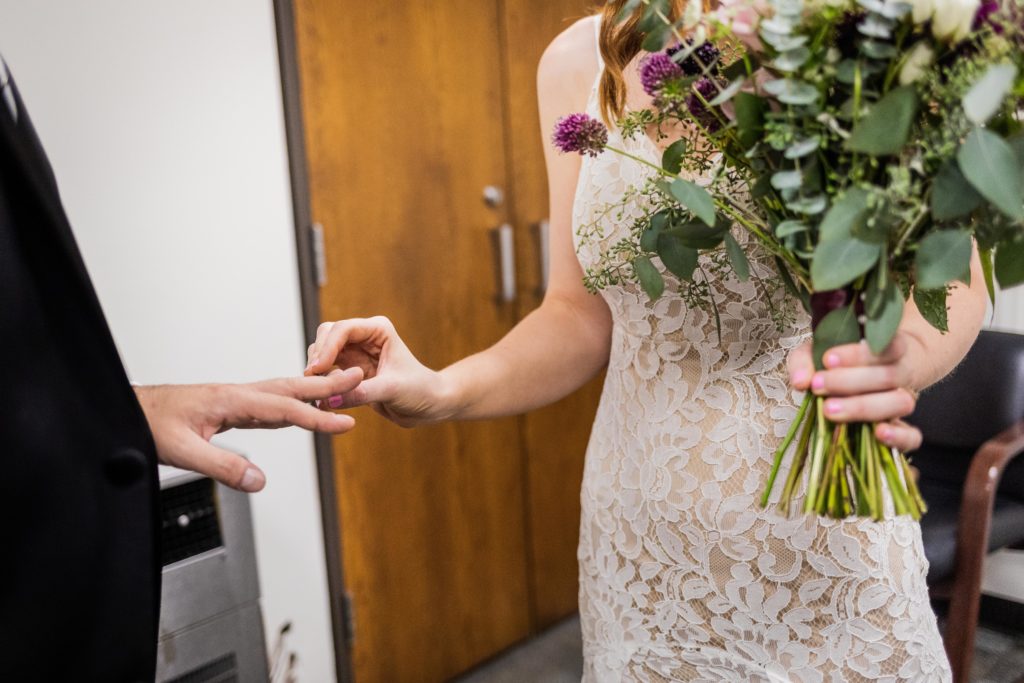 Bride putting the ring on the groom's finger in city hall
