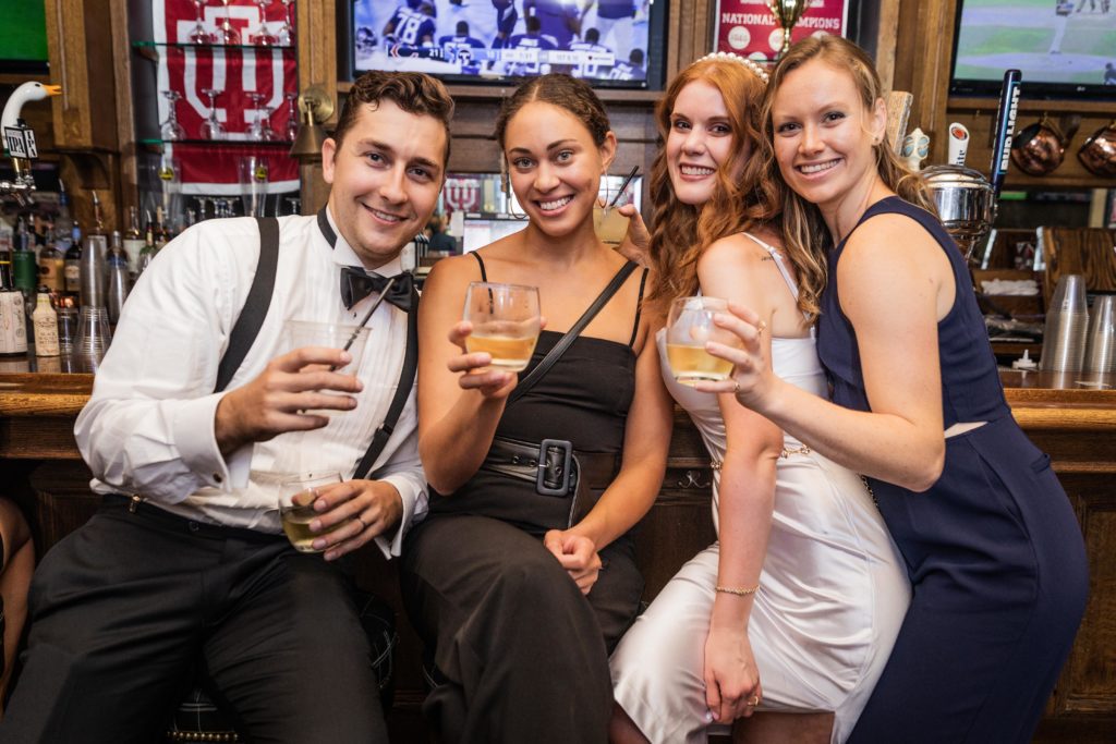 Bride and groom posing for photos with friends at the bar