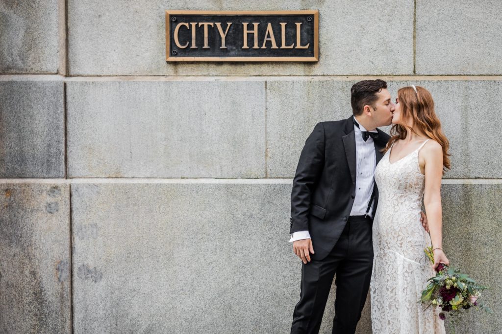 Couple kissing in front of the City Hall sign in Chicago