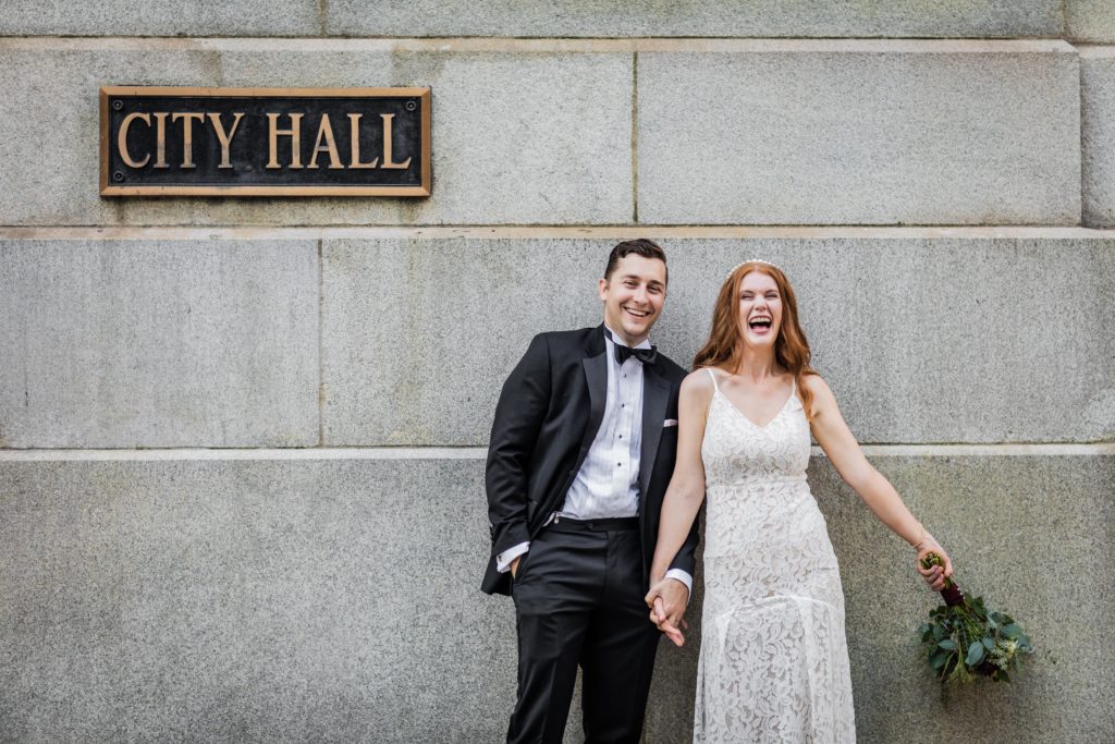 Couple laughing in front of the City Hall sign in Chicago