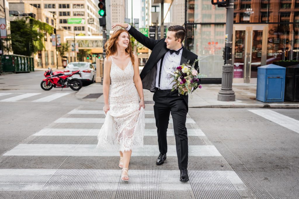 Groom touching the bride's hair while they cross the street after their Chicago City Hall wedding 
