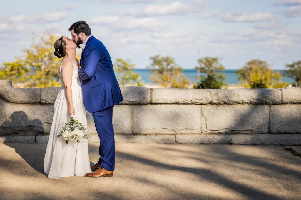 Bride and groom kissing by the lakefront