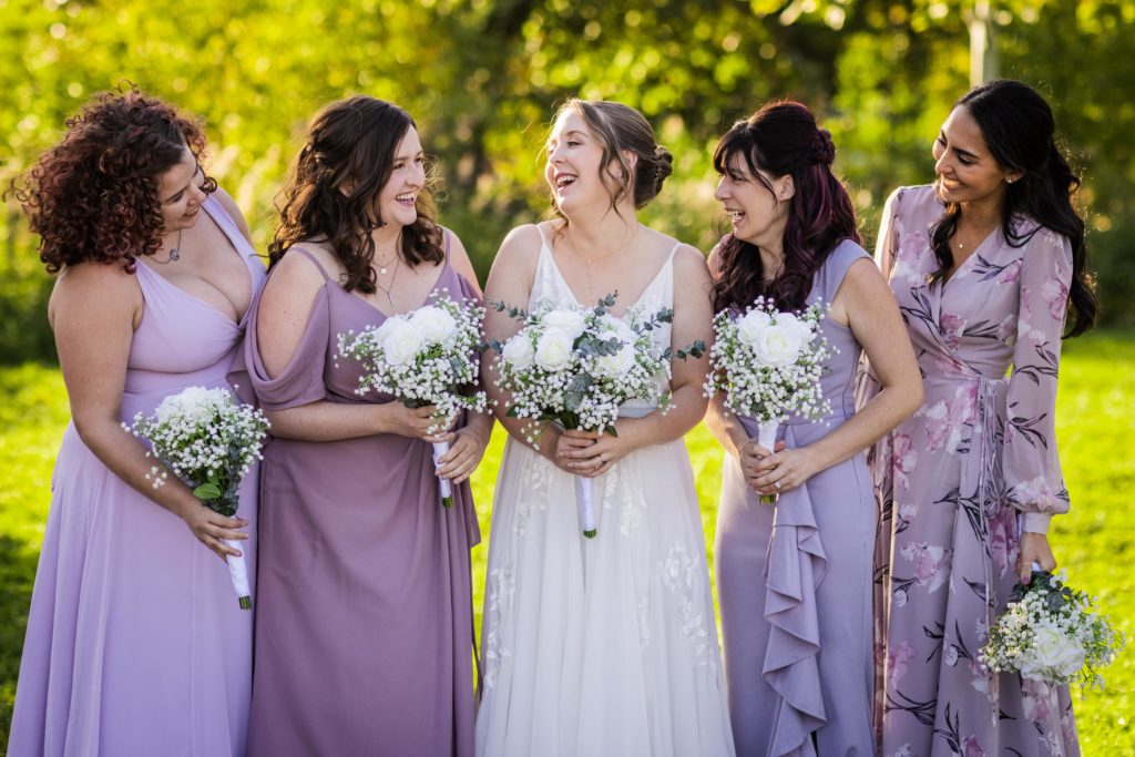 Bride laughing with her bridesmaids in the park