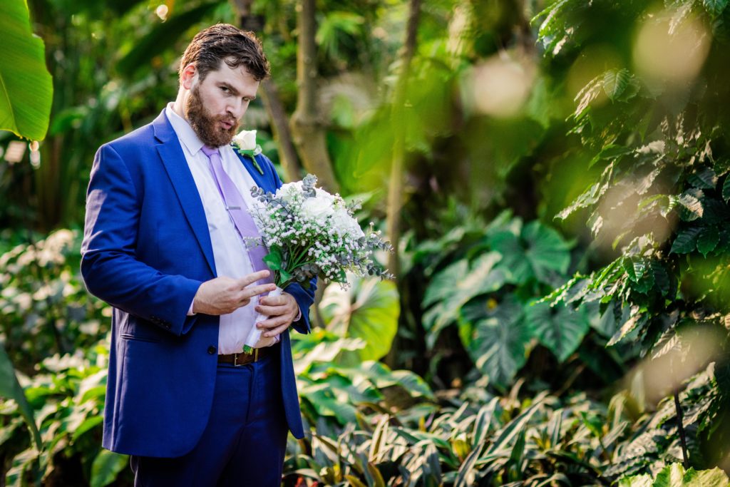 Groom posing with the bouquet at the Lincoln Park Conservatory