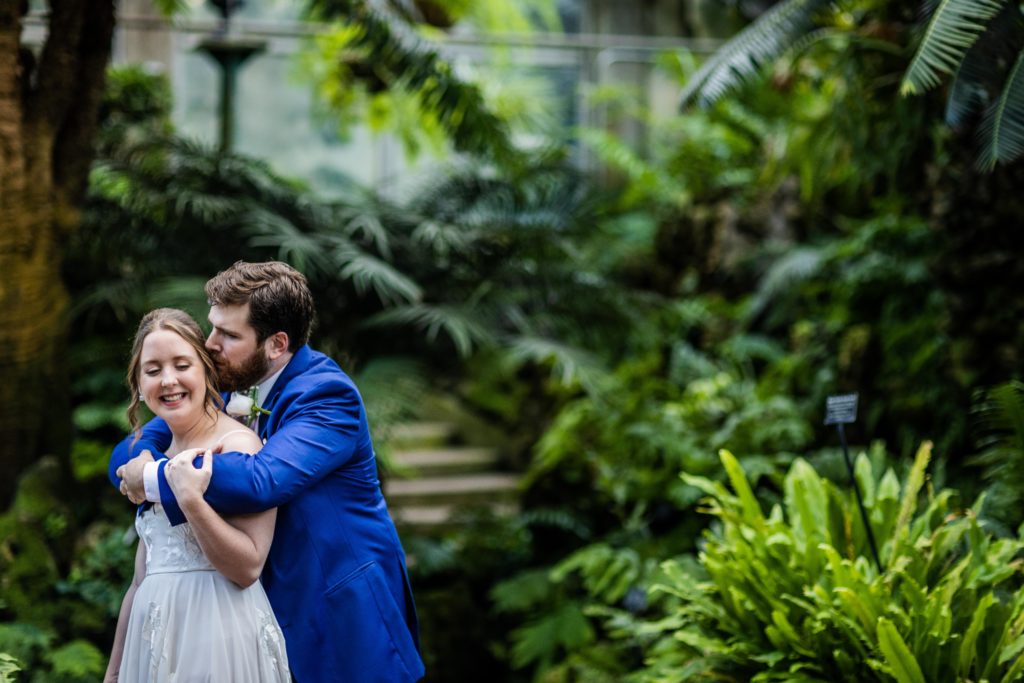 Groom kissing bride from behind at theLincoln Park Conservatory