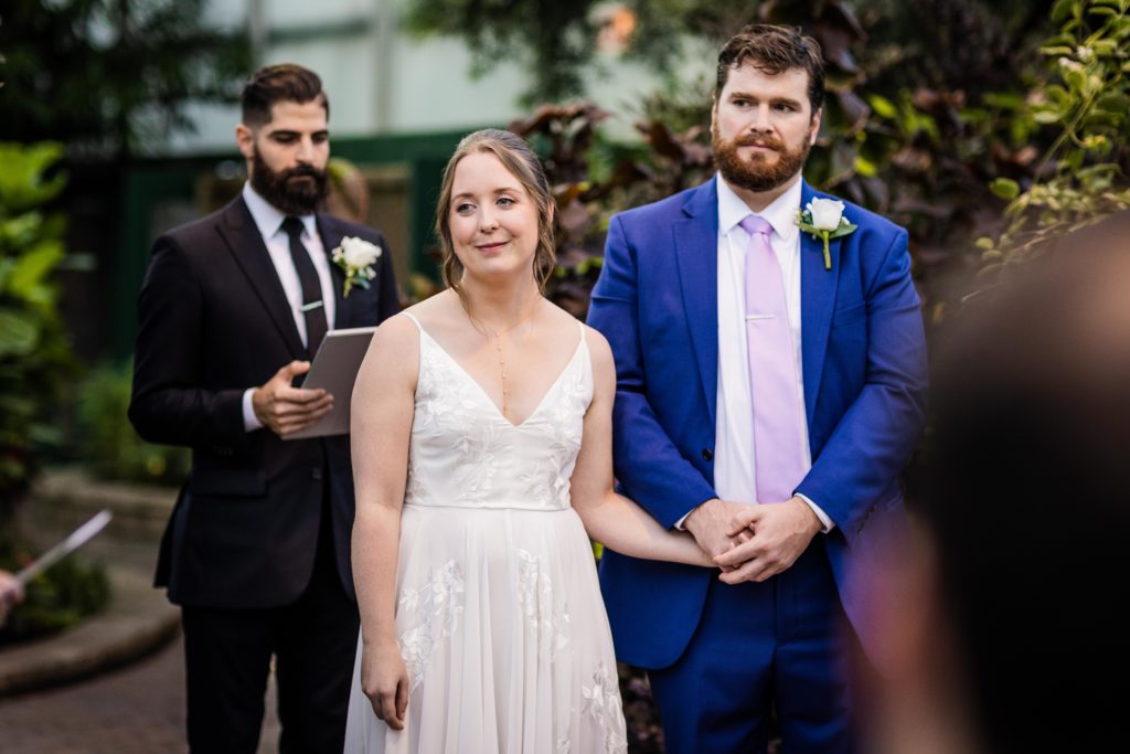 Bride and groom smile as they listen to a speech at their ceremony