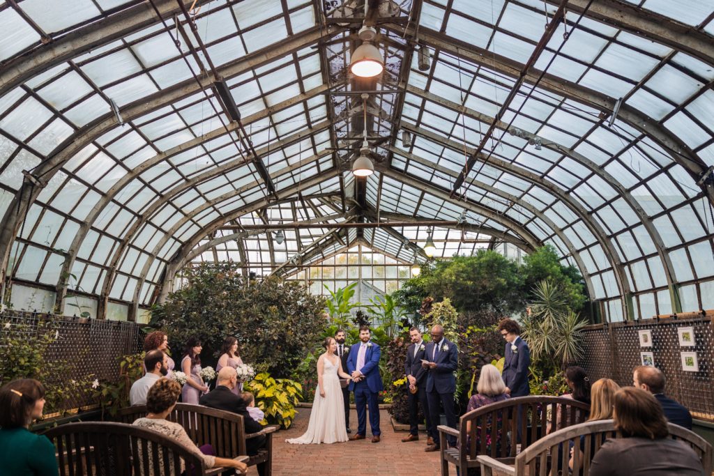 Bride and groom watch a speech during their Lincoln Park Conservatory wedding