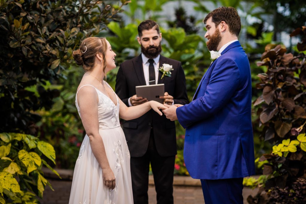 Groom placing the ring on the bride during their Lincoln Park Conservatory wedding
