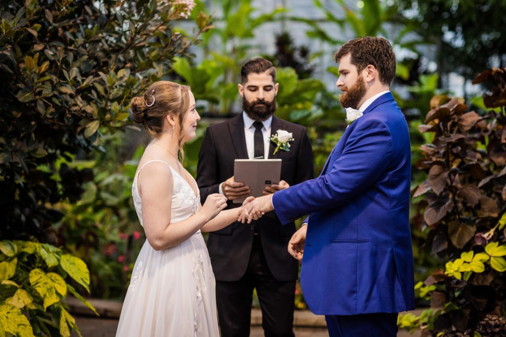 Bride placing the ring on the groom during their Lincoln Park Conservatory wedding