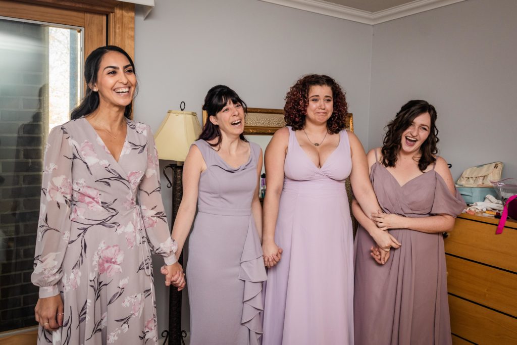 Bridesmaids smiling while seeing the bride for the first time