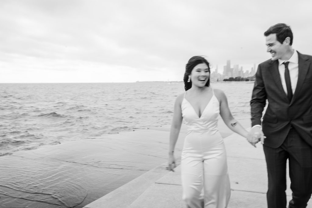 Bride and groom laughing and smiling while walking down the lakefront