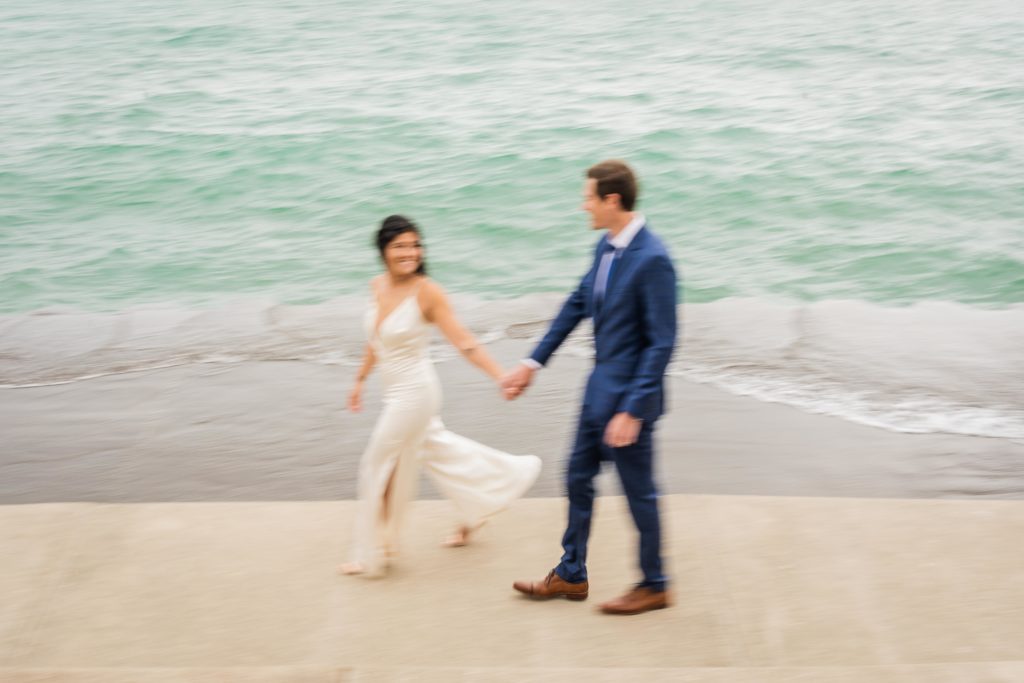 Couple holding hands walking down the lakefront after their elopement in Chicago